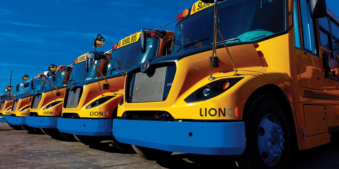 Lion electric Manufacturing Photo of a row of Lion electric school buses against a blue sky
