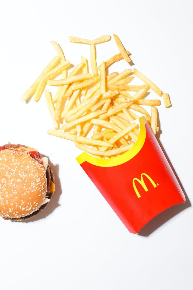 a burger and mcdonalds fries on white surface