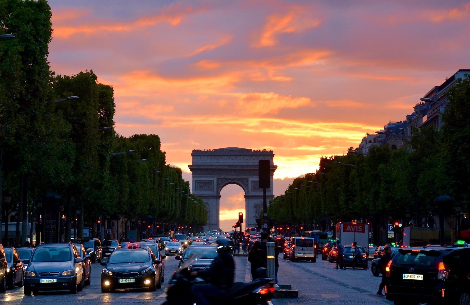 busy street with cars along the Arc de Triomphe