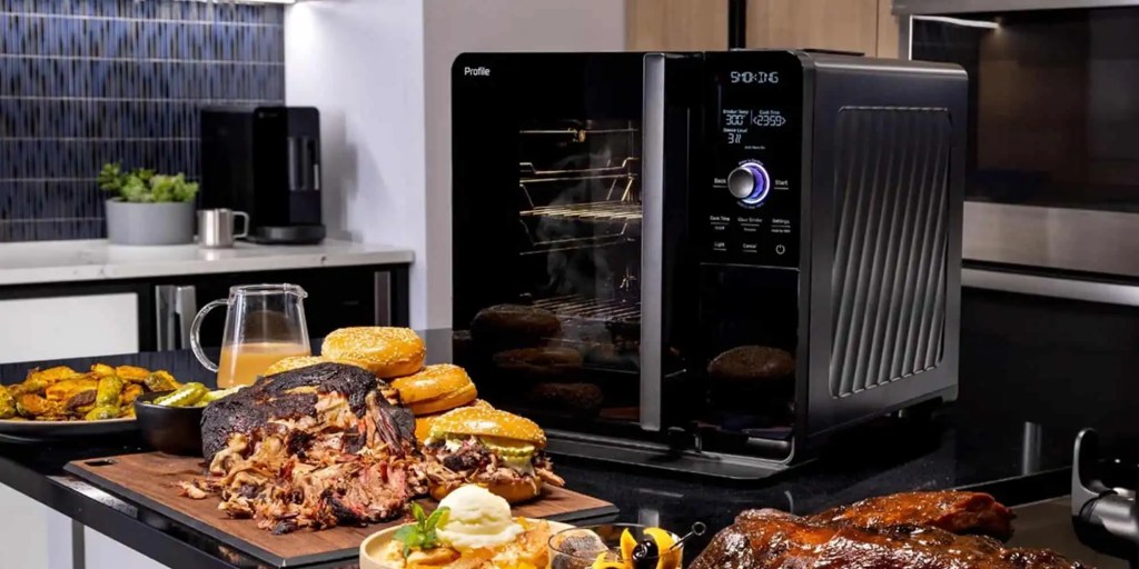 GE Profile Smart Indoor Smoker sitting on countertop surrounded by fresh BBQ