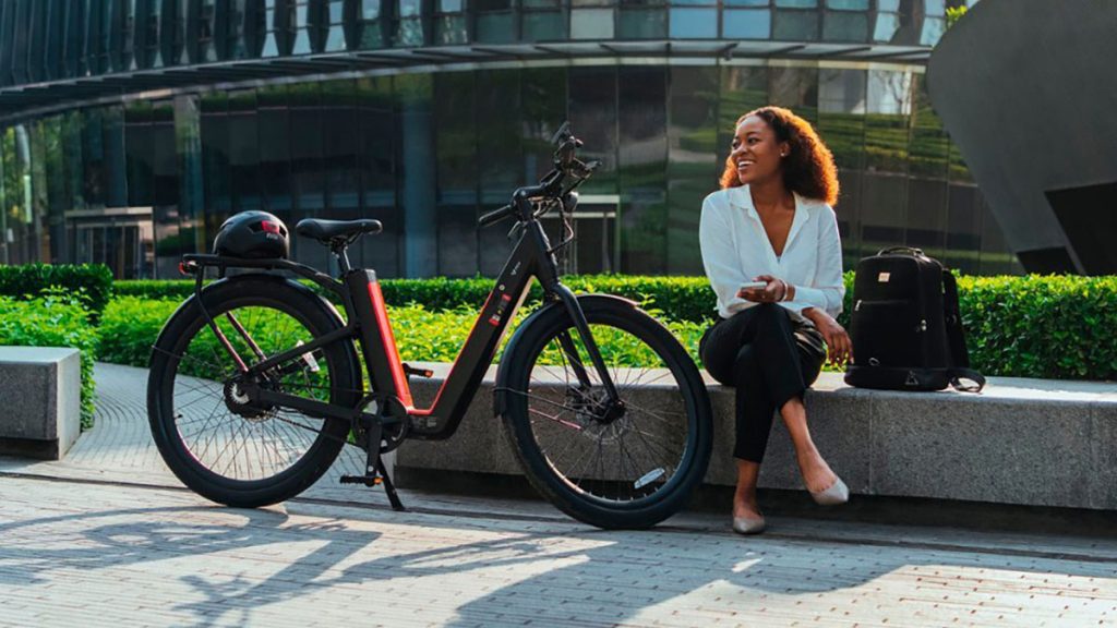 NIU BQi-C3 Pro e-bike parked next to stone bench with woman sitting, within post for Hiboy Ex6 Step-Thru e-bike