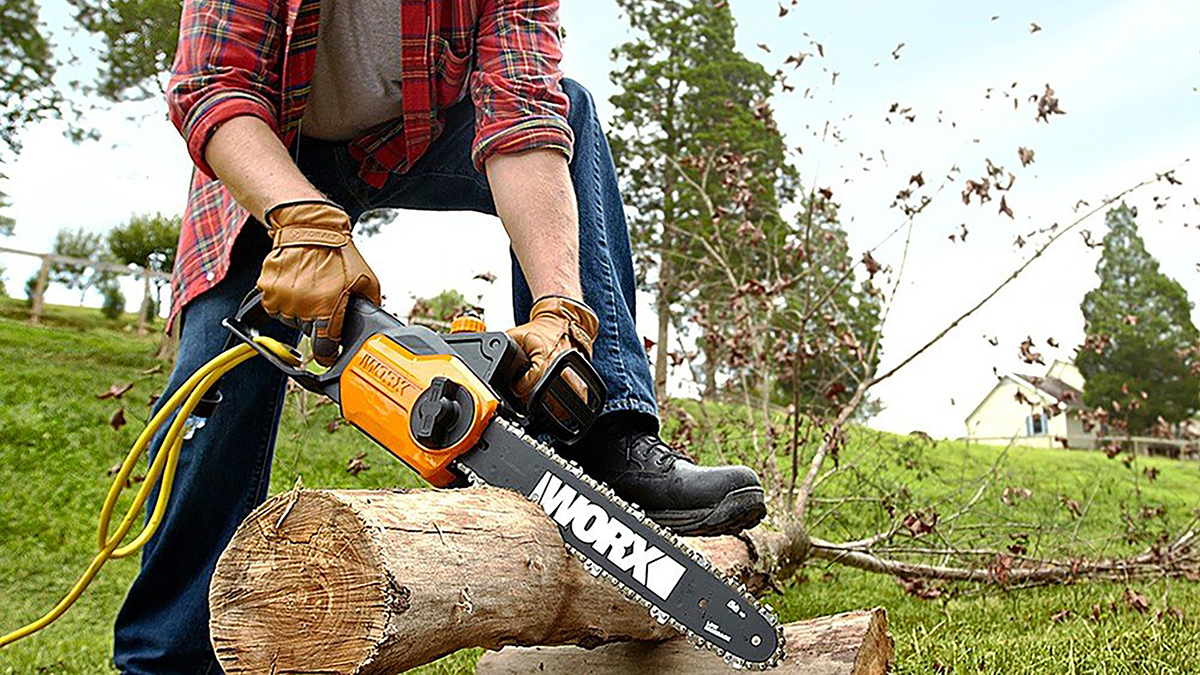 WORX 8A 14-inch corded electric chainsaw being used by man to cut thick tree branch within post for ALLPOWERS International Pet Day Sale