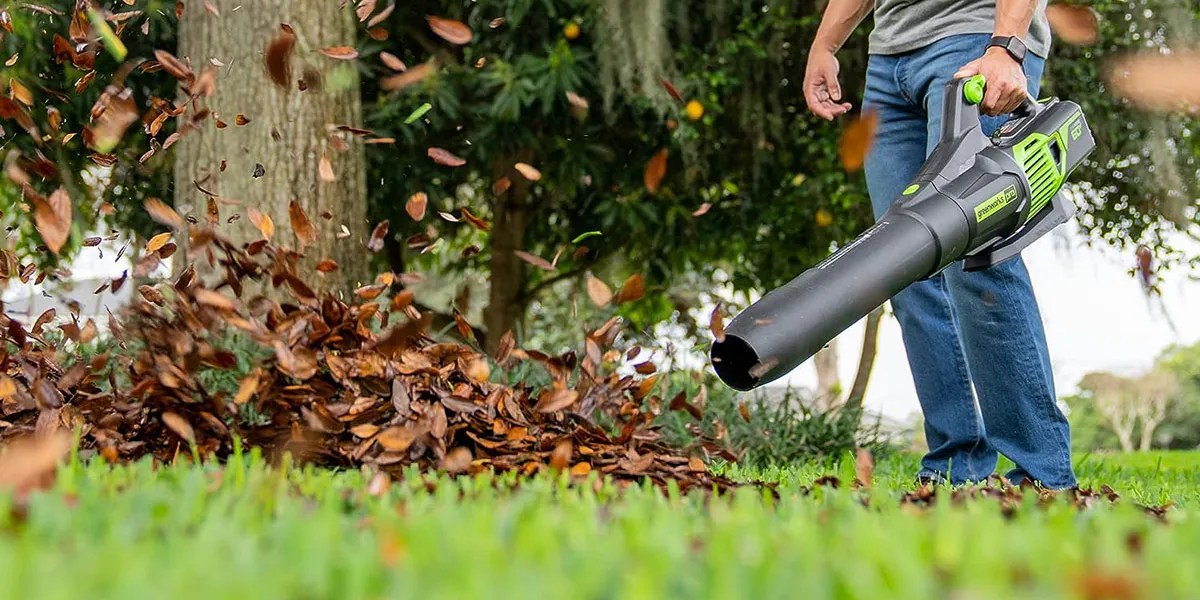 Greenworks 80V 730 CFM cordless electric leaf blower being used in yard to move leaves within post for Super73 RX electric motorbike