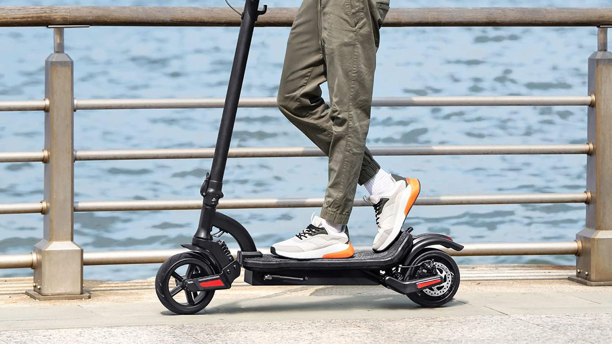 Jetson Canyon folding electric scooter being ridden on boardwalk with ocean in background, within post for Hover-1 Altai Pro R750 e-bike