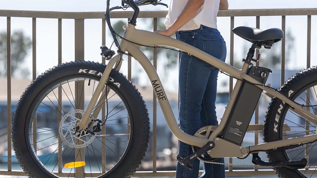 The Fat Murf e-bike parked against railing with woman looking into background, within post for Jackery Explorer 600 Plus power station