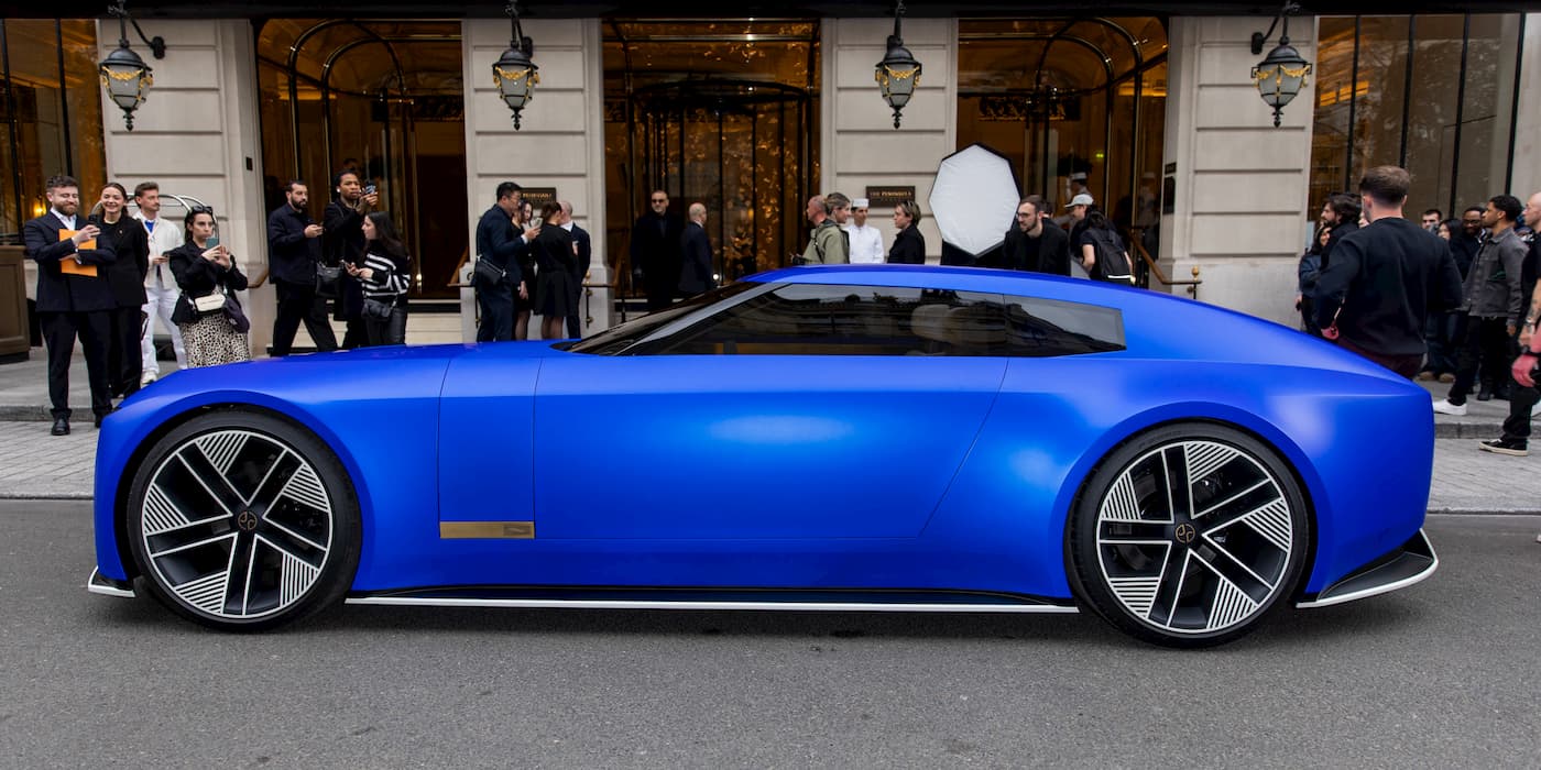 Front view of the Jaguar Type 00 EV on display, with a group of people walking by.