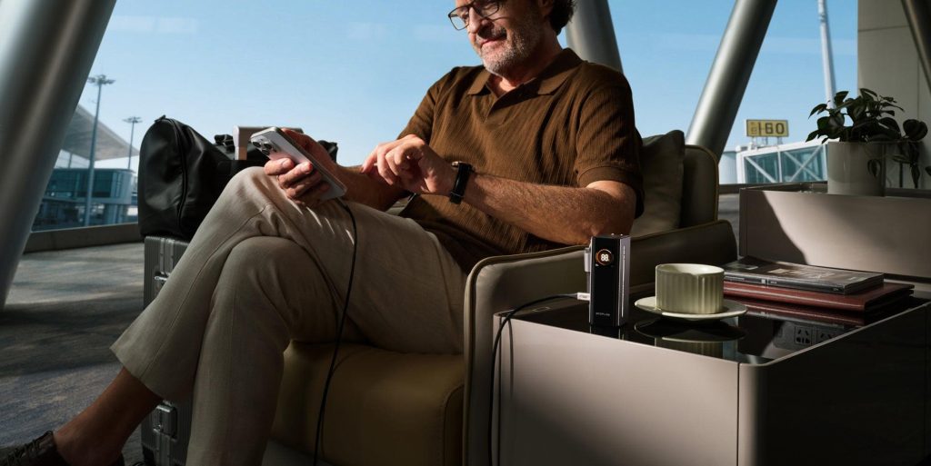man sits in airport with EcoFlow RAPID power bank charging phone