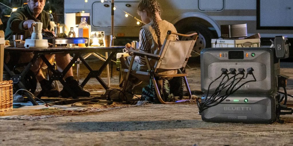 father and daughter at camping table surrounded by lights powered by Bluetti Apex 300 power station