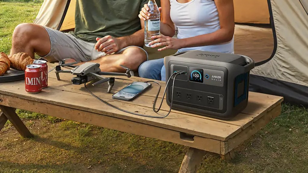 man and woman charging phone and drone outdoors with anker solix c1000x gen 2 power station