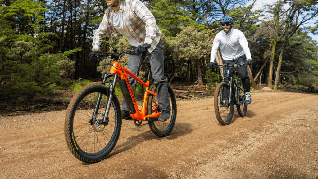 two men riding Velotric Summit 1 e-bikes down dirt trail