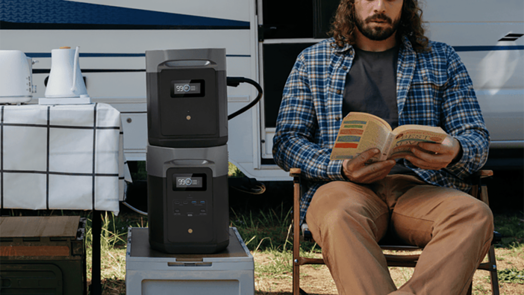 man reading book while camping with EcoFlow DELTA 2 Max power station and expansion battery