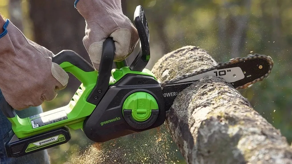 man using Greenworks 24V 10-inch chainsaw to cut up tree 
