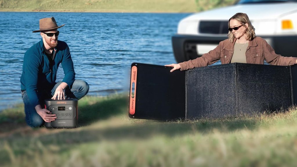 man and woman setting up Jackery power station with solar panel outdoors