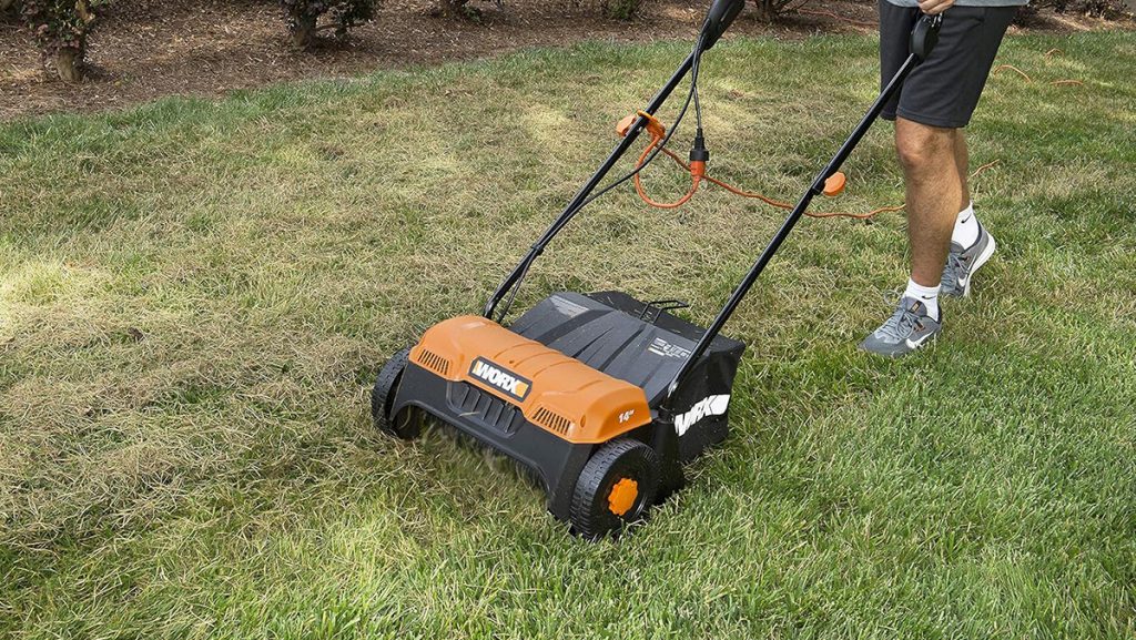 Man using Worx corded dethatcher in yard