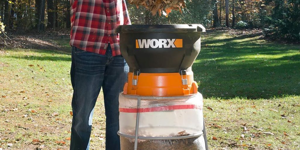 Man dropping leaves into Worx electric leaf mulcher in yard