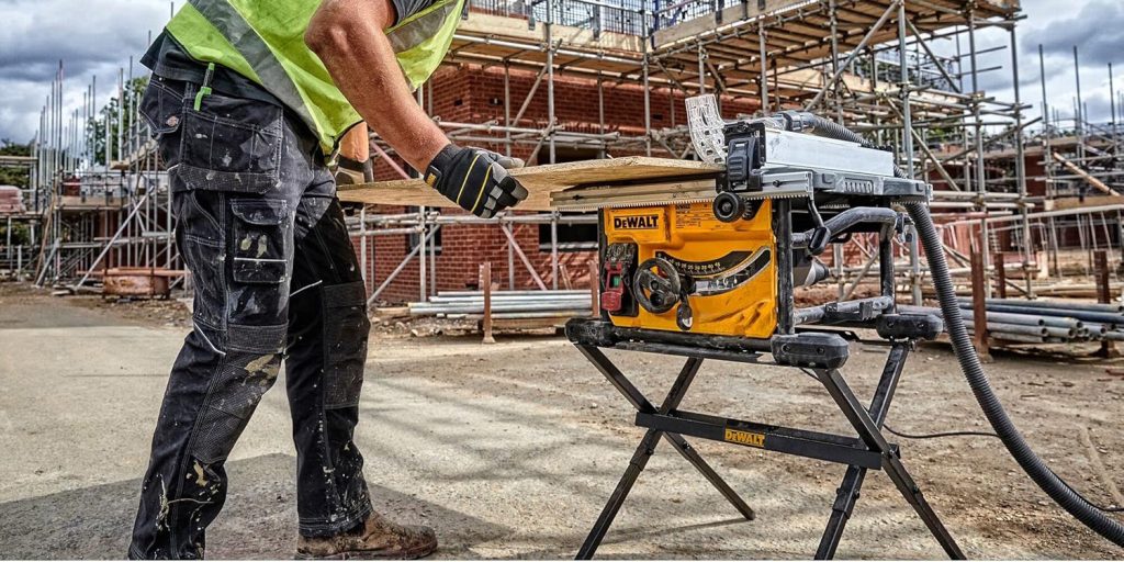man using dewalt compact table saw at jobsite to cut plywood