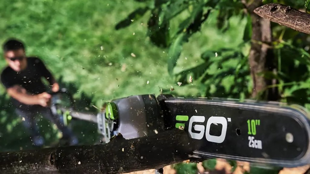 man using EGO pole saw to cut tree branch