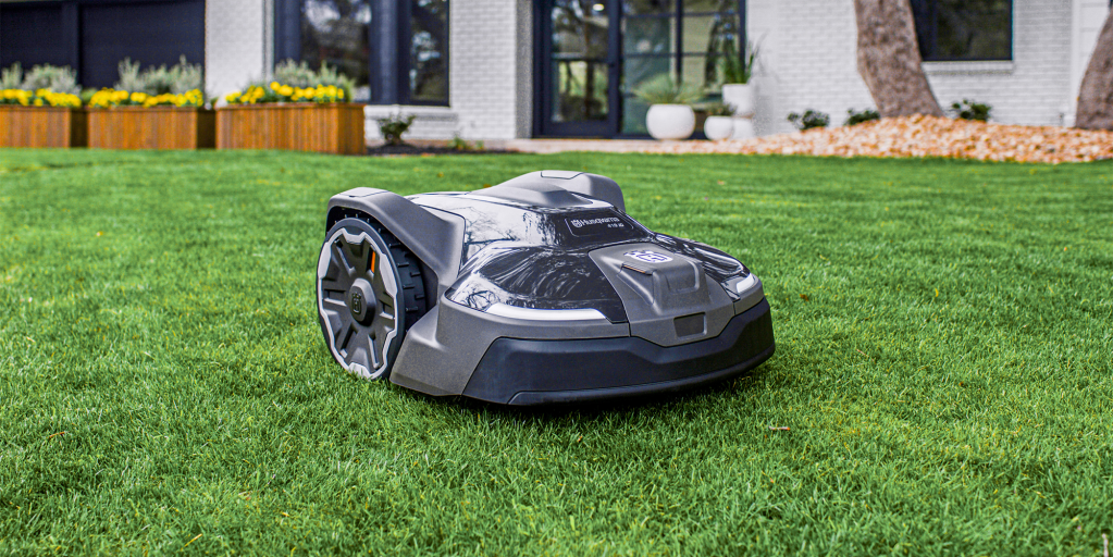 Husqvarna robotic lawn mower in grass in front of house