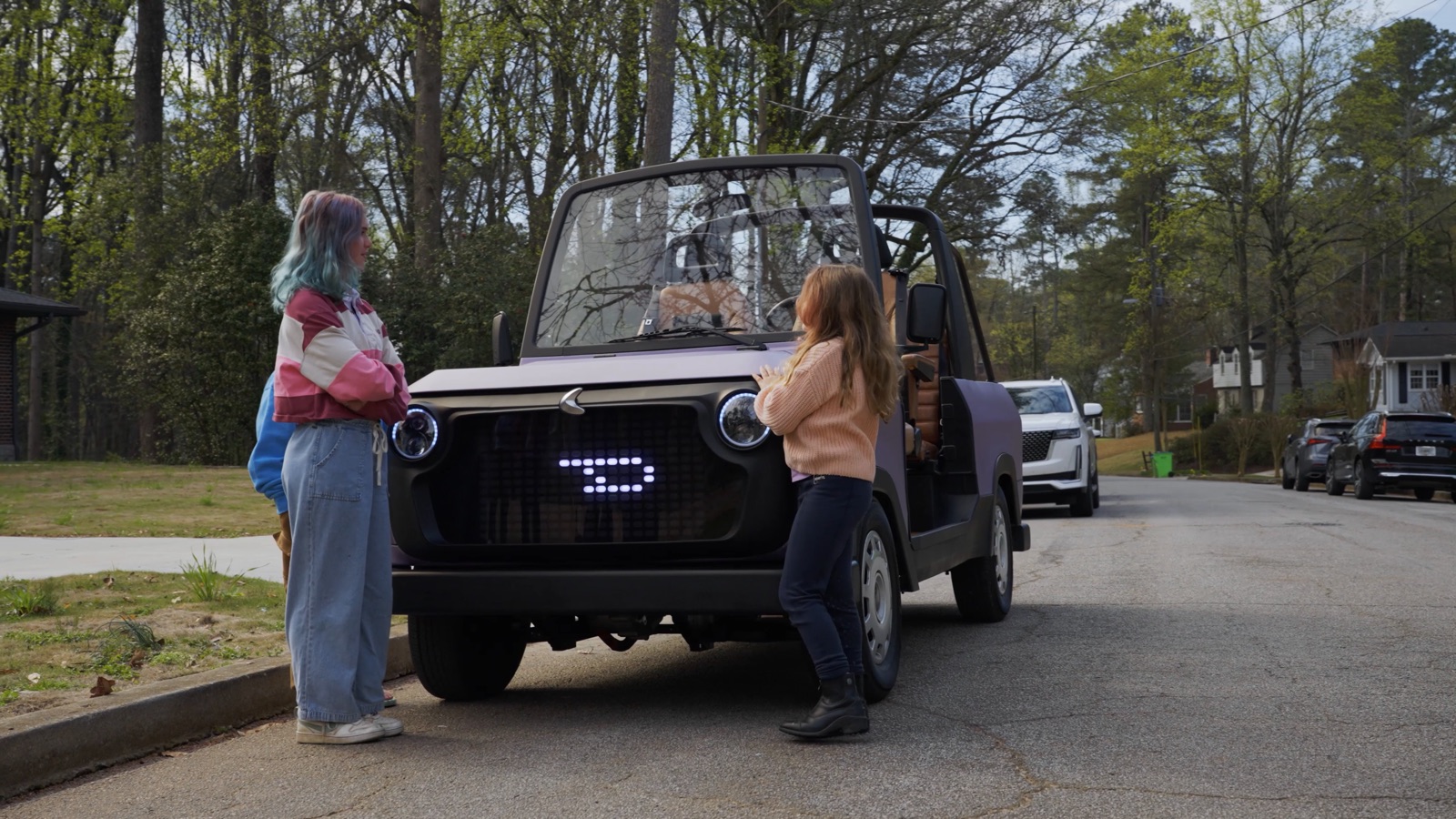 Chip Motors’ electric life utility vehicle driving on a tree-lined neighborhood street