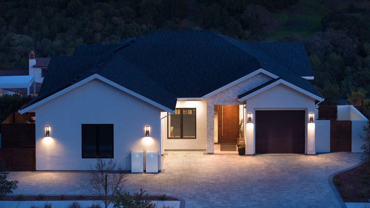 Two Tesla Powerwall units mounted outside a home at dusk
