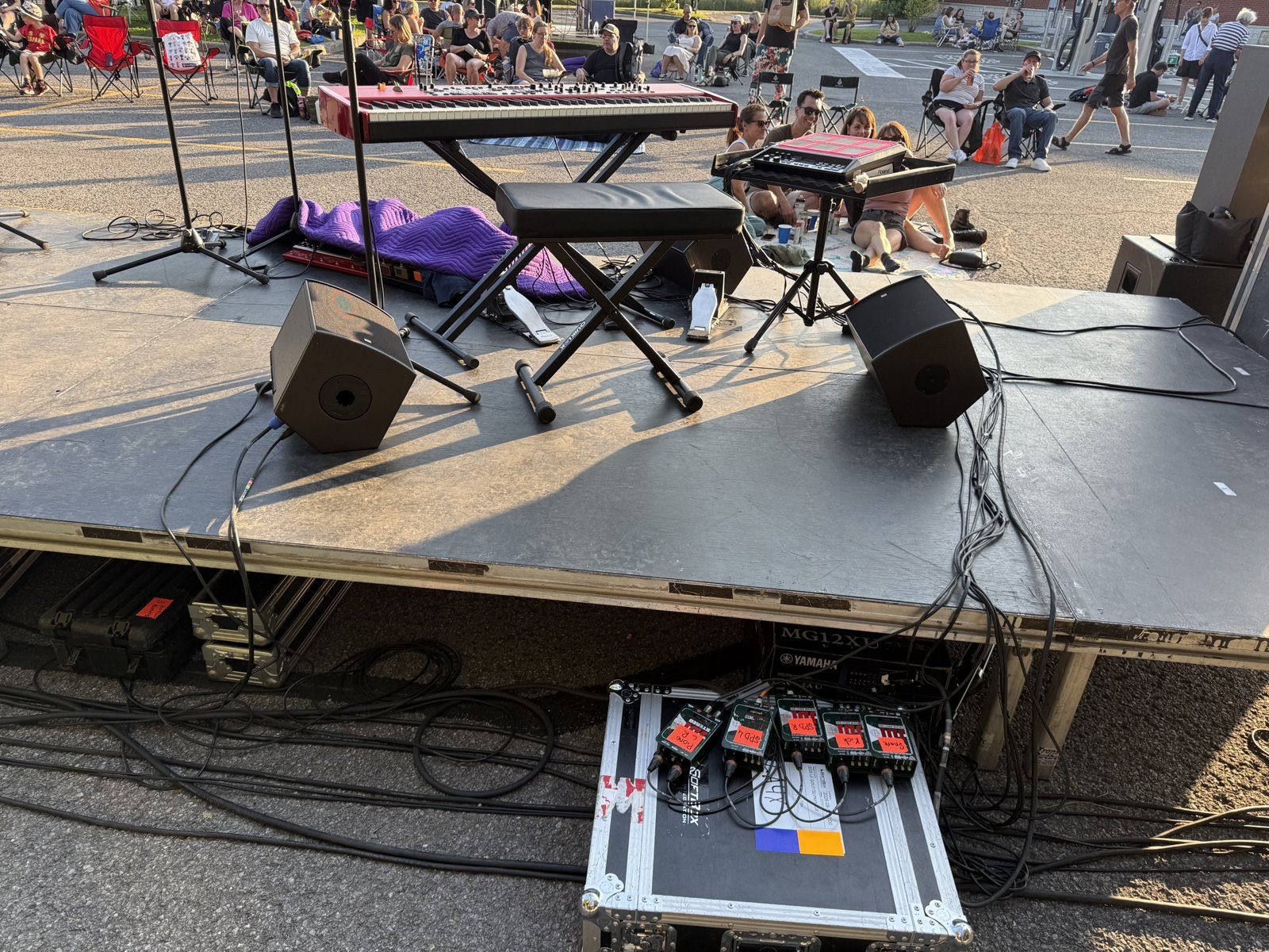 Stage set up in the IGA parking lot in Saint-Henri with the crowd seated on the asphalt