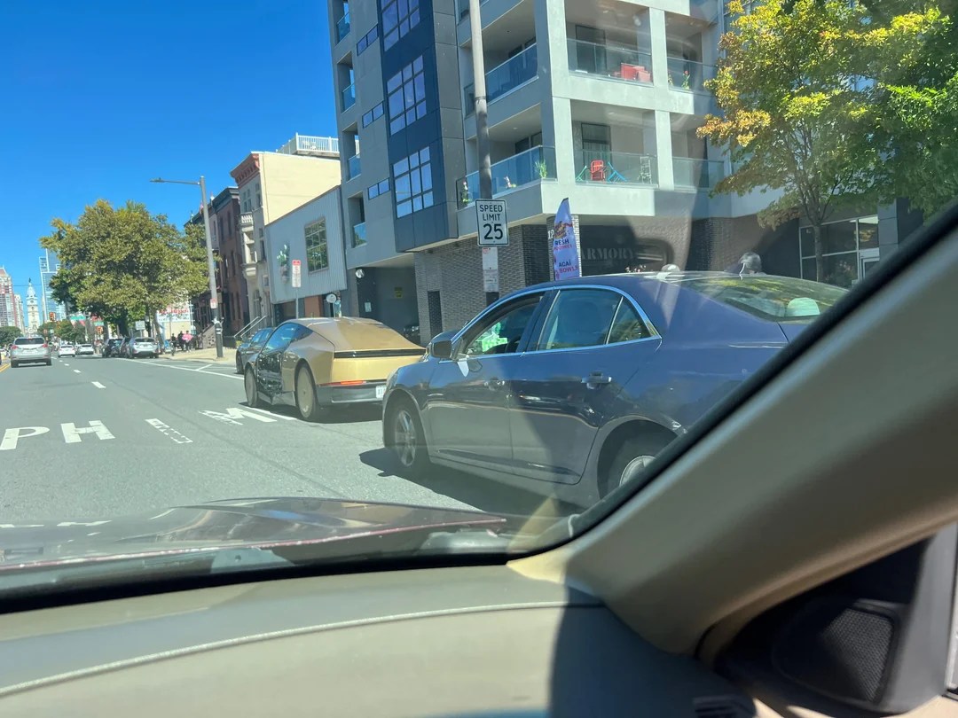 Tesla Cybercab seen from behind on South Broad Street in Philadelphia with a dark sedan stopped behind it